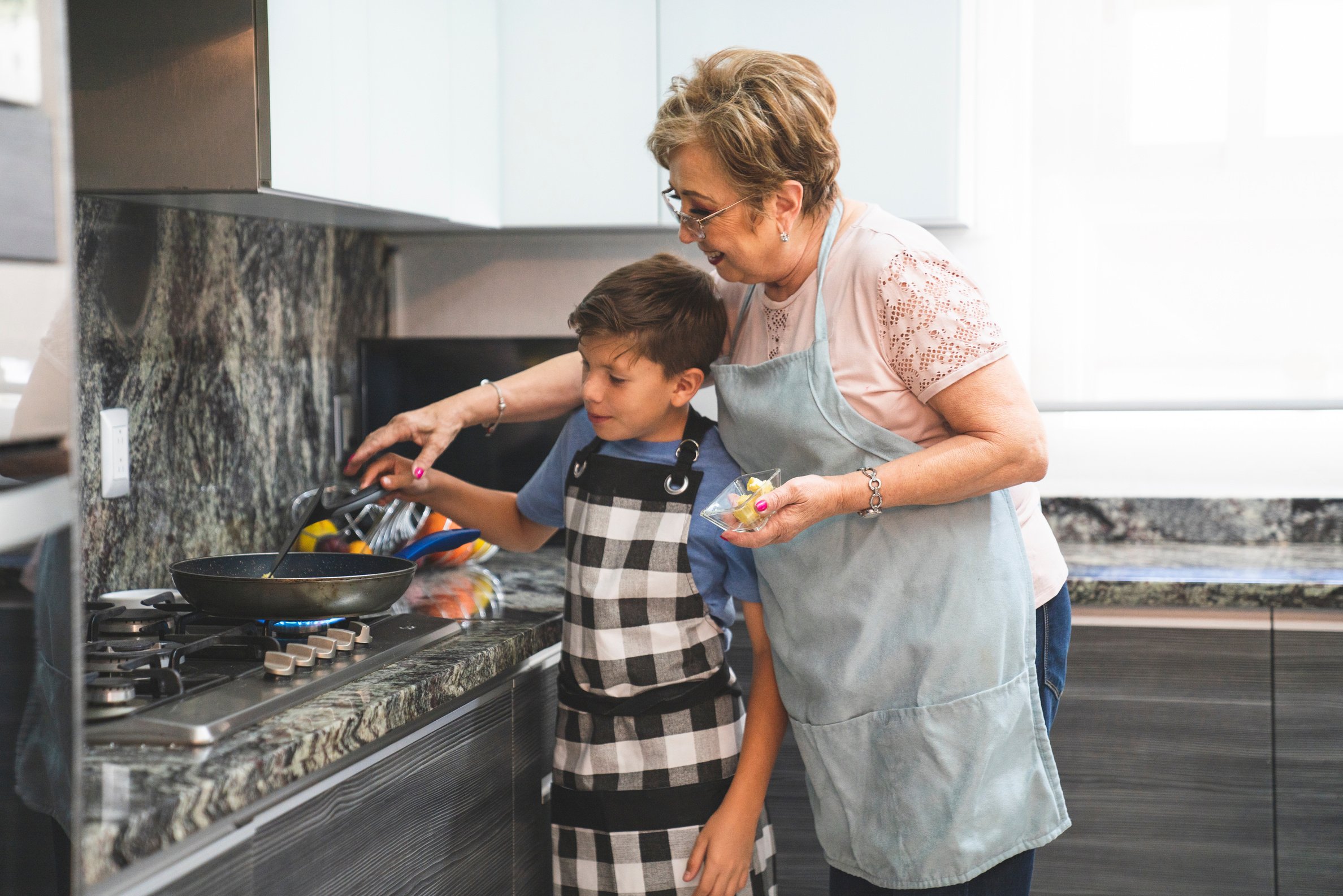 Boy and Elderly Woman Wearing Aprons Cooking 